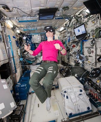 a woman in pink shirt sitting on top of a space station with lots of electronics