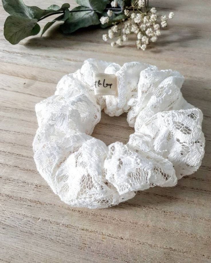 a white lace scrunffle on top of a wooden table next to some flowers