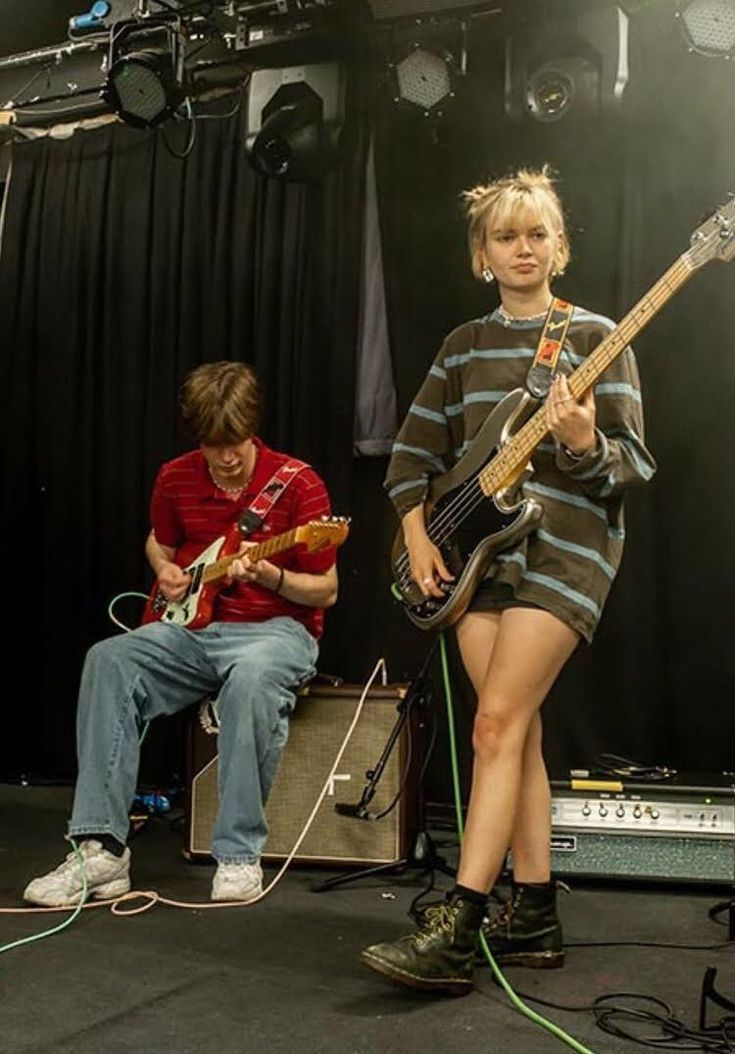 two young men are playing guitars on stage