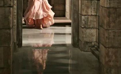 a woman in a pink dress is walking through an archway