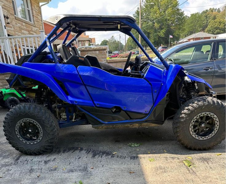 a blue buggy is parked in front of a house with two cars behind it