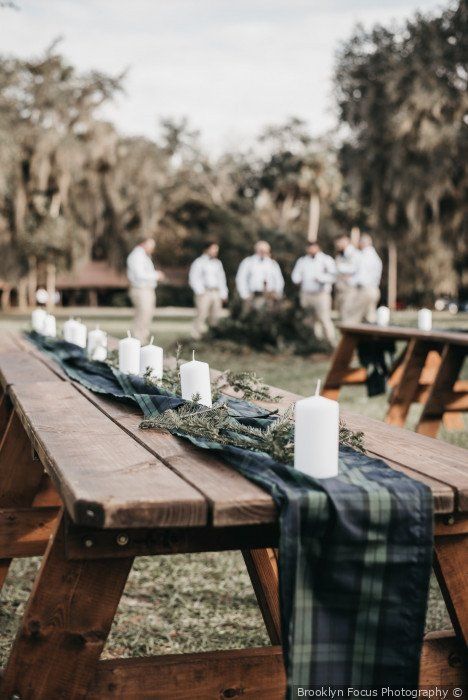 a long wooden table with candles on it in front of some other people standing around