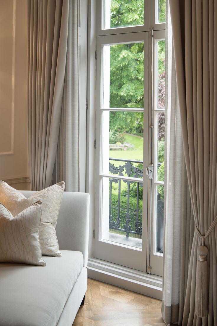 a white couch sitting in front of a window with curtains on the windowsills