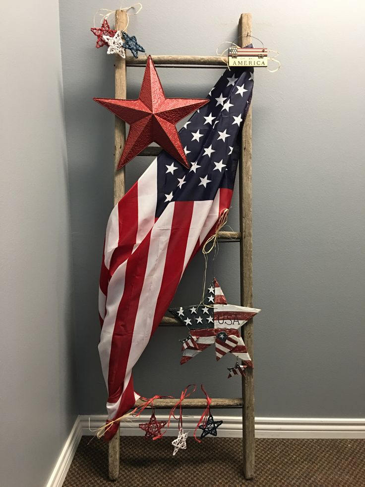 an american flag hanging on a ladder in the corner of a room with other decorations