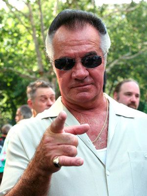 a man in sunglasses giving the thumbs up sign with other people behind him looking on