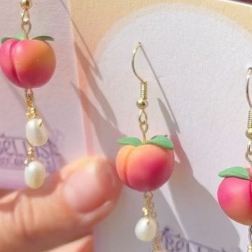 a pair of earrings with peaches and pearls hanging from them