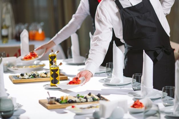 a person in an apron preparing food at a table with plates and utensils