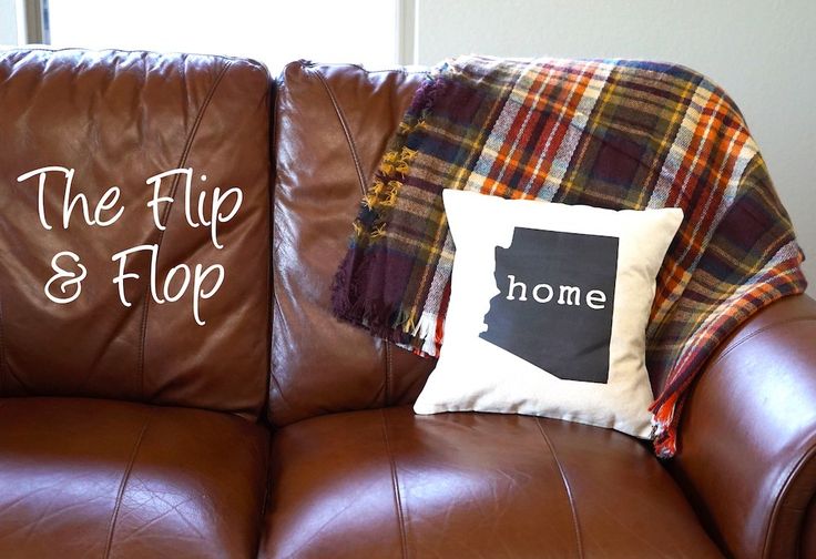 two pillows on the back of a brown leather couch with state pillow and plaid blanket