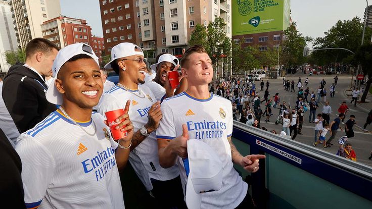 the men are posing for a photo in front of some people and one is holding a drink