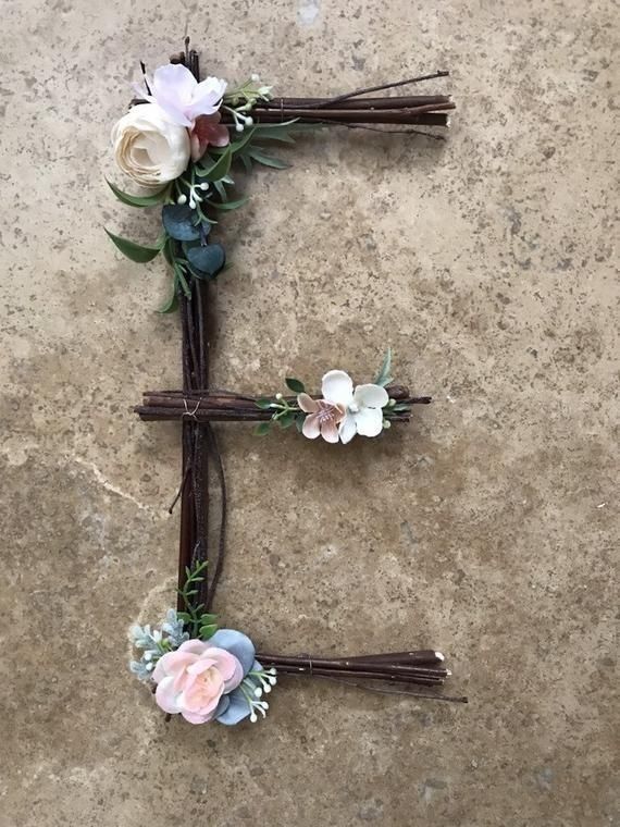 flowers are arranged in the shape of the letter e on a stone surface with twigs