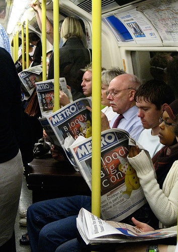 people are sitting on the subway and reading newspapers