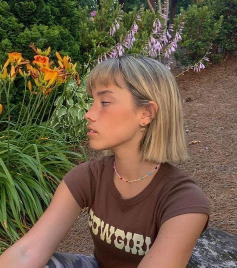 a young woman sitting on a rock in front of some flowers and plants with her head turned to the side