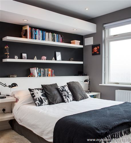 a bedroom with black and white decor, bookshelves and a bed