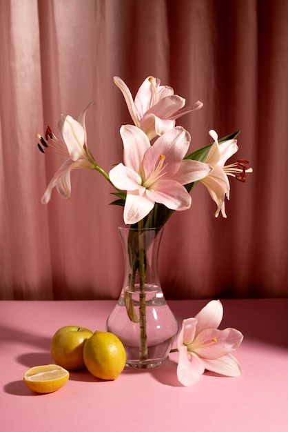 a vase filled with pink flowers next to lemons