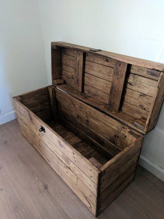 an empty wooden box sitting on top of a hard wood floor next to a wall