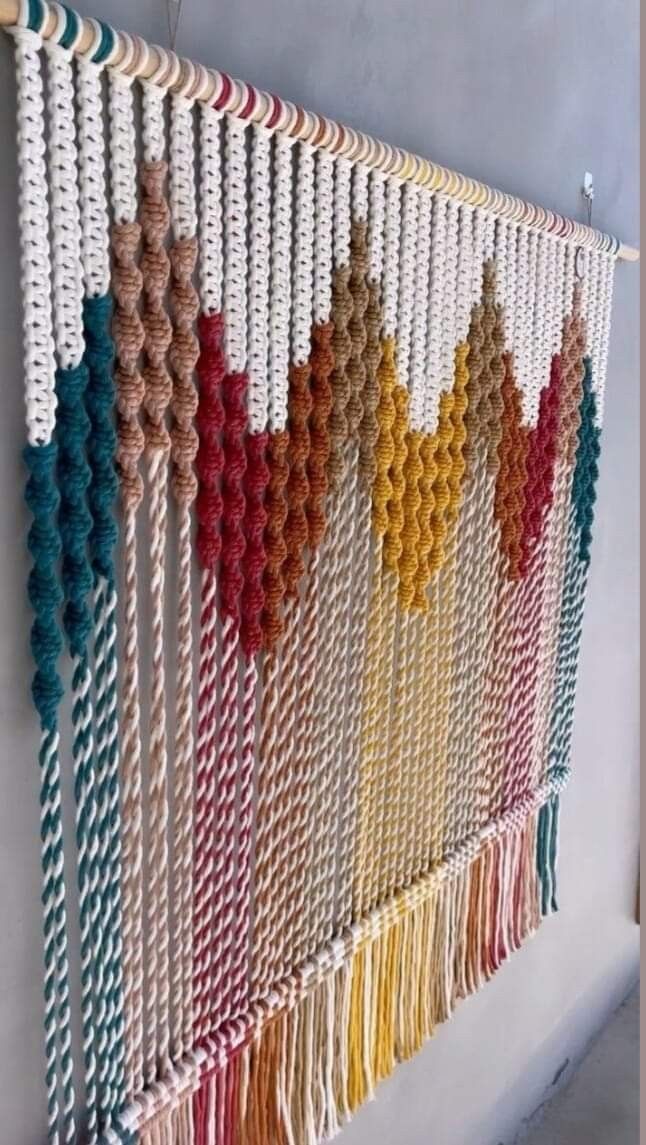 a wall hanging made out of macrame balls and yarn with different colors on it