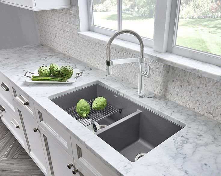 a kitchen sink with two green vegetables on the counter top next to an open window