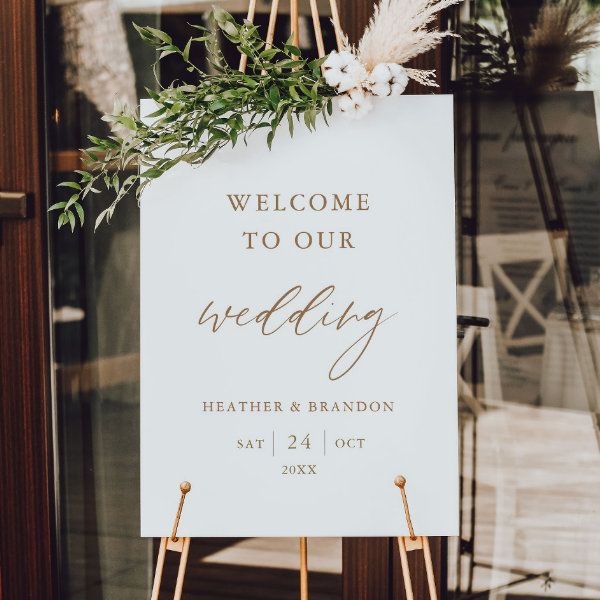 a welcome sign hanging from the side of a wooden door with greenery on it