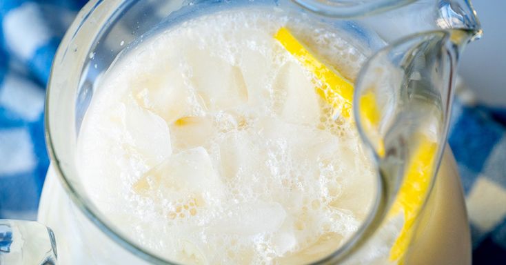 a pitcher filled with ice and lemon wedges on top of a checkered table cloth