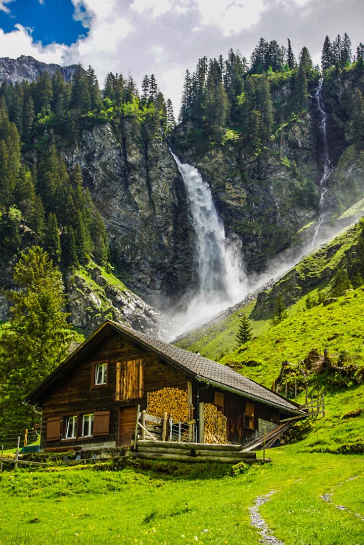 a house in the mountains with a waterfall coming out of it