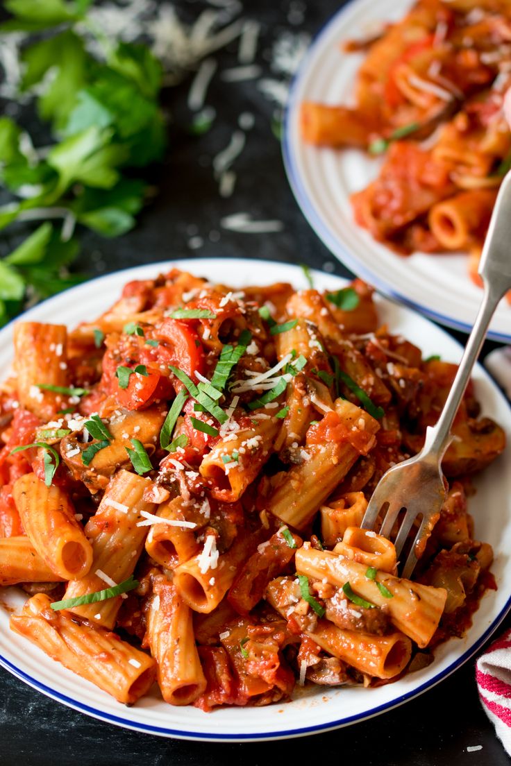 two plates of pasta with sauce and parmesan cheese