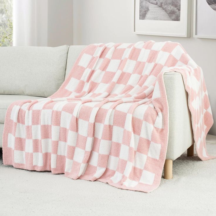 a pink and white checkered blanket sitting on top of a couch