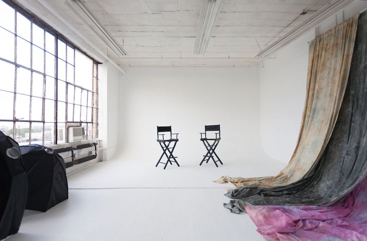 two black chairs sitting on top of a white floor in front of a large window