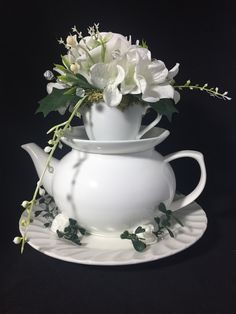 a white vase with flowers in it sitting on a saucer next to another bowl