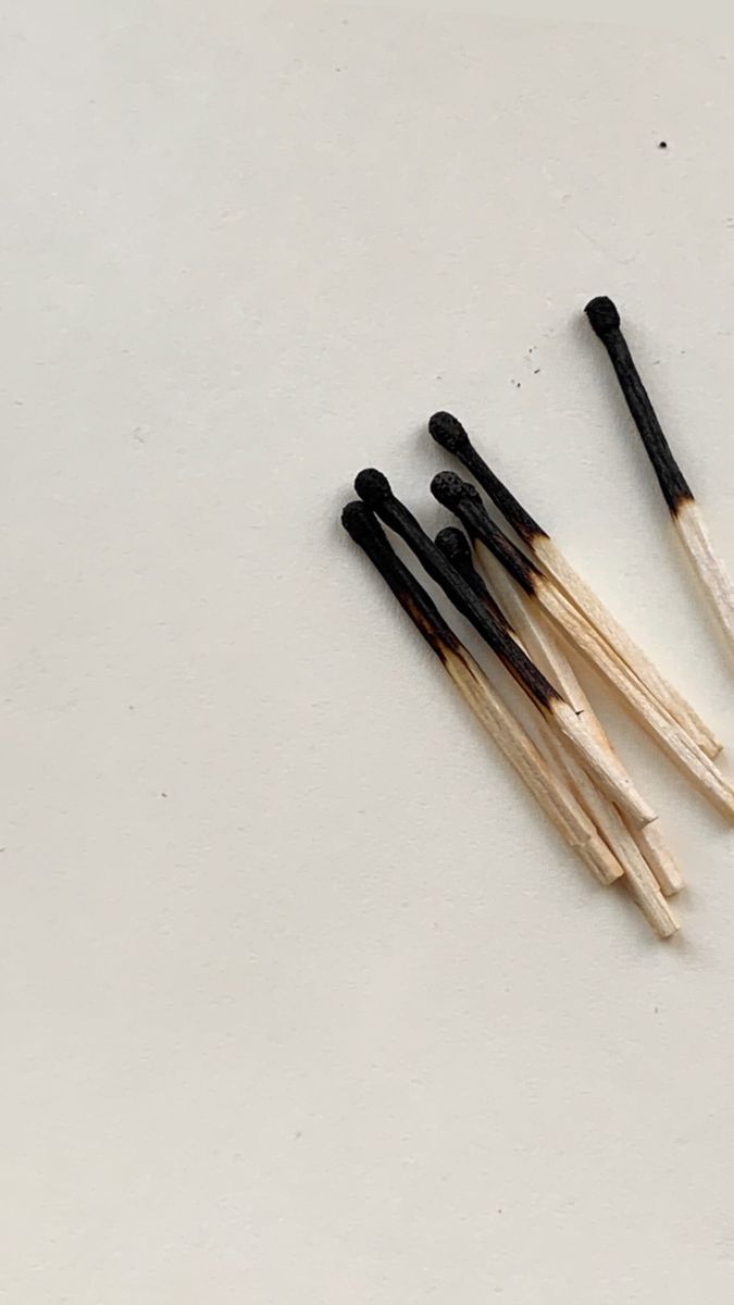 five black and white matchesticks on a white surface