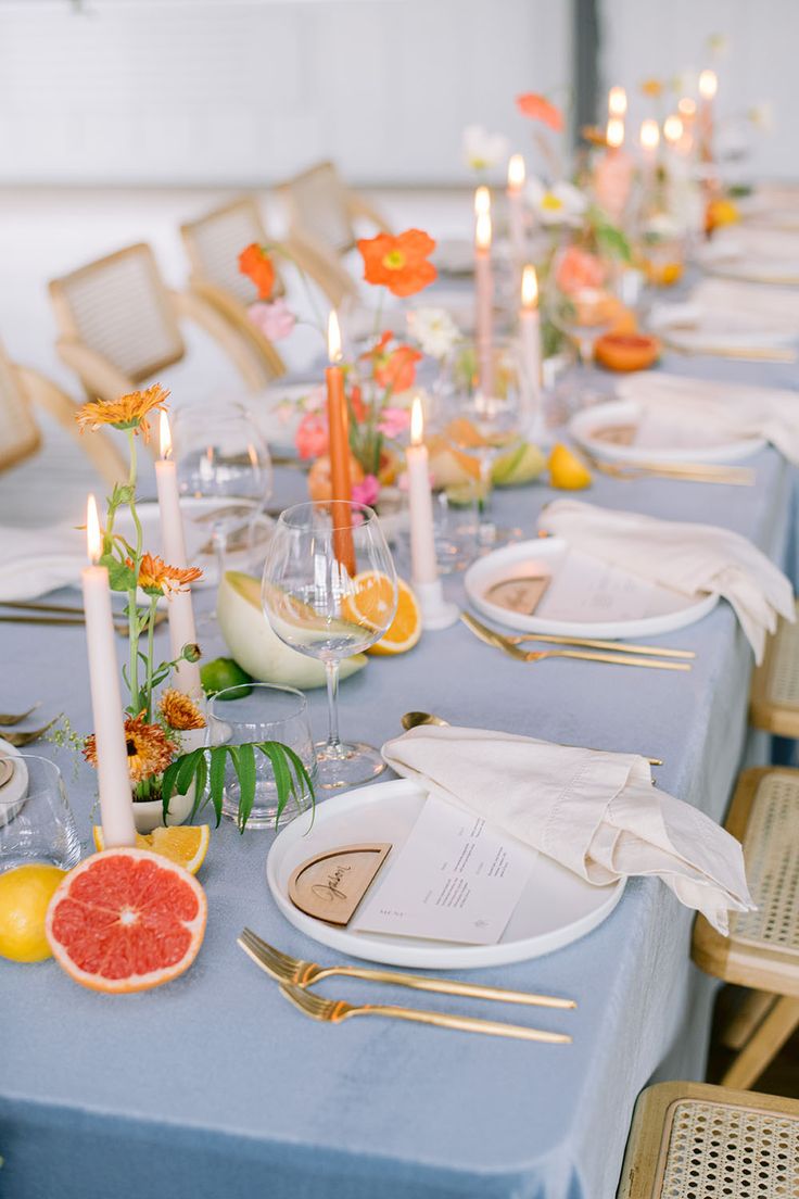 the table is set with plates, silverware and grapefruits