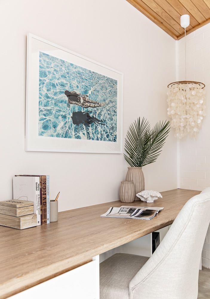 a wooden desk topped with a white chair next to a painting