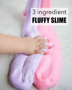 a baby's hand is touching the pink and purple slime