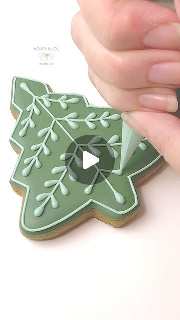 a person is decorating a cookie with green icing