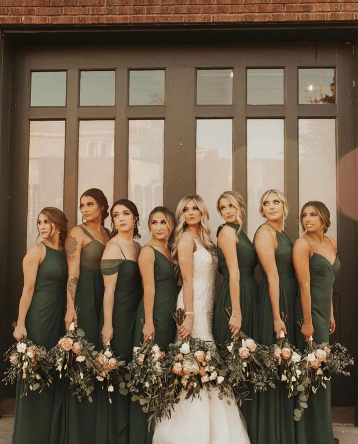 a group of women standing next to each other in front of a door wearing green dresses