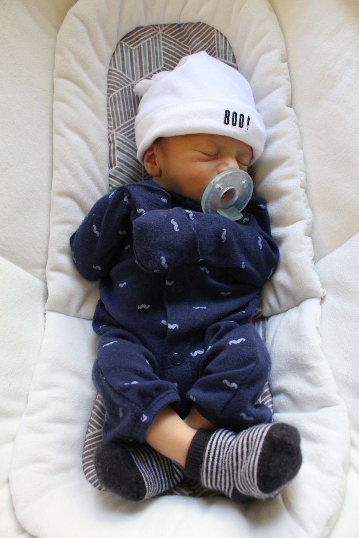 a baby is sleeping with a pacifier in it's mouth and wearing a hat