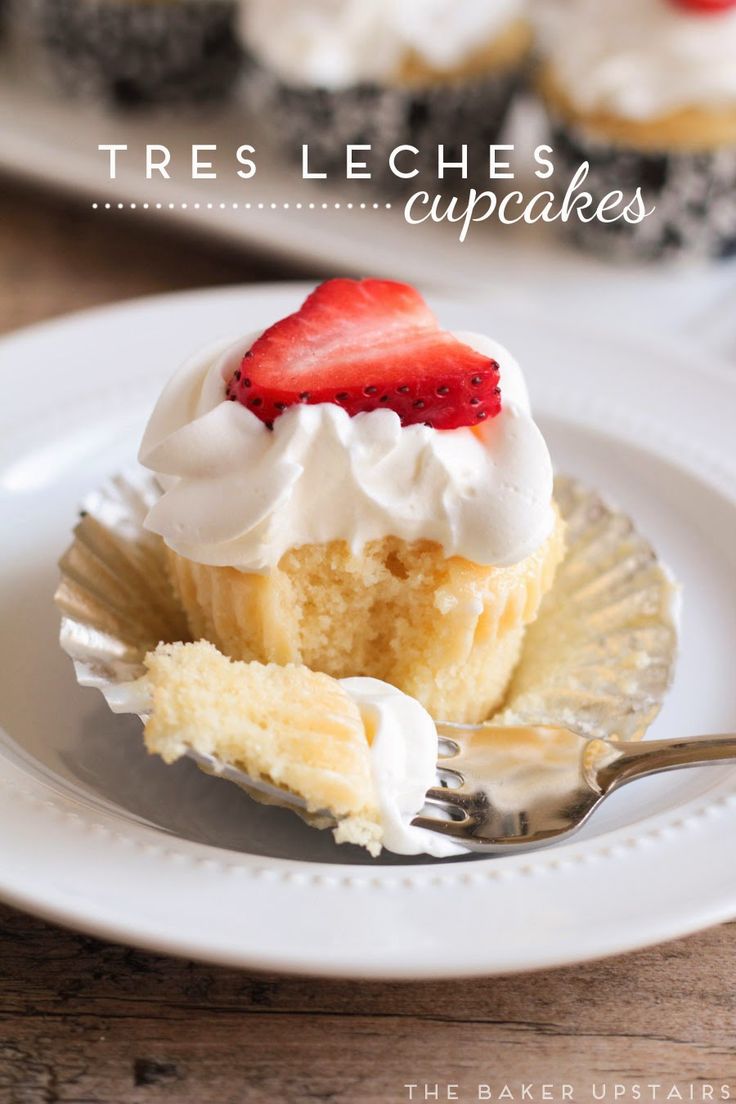 a close up of a plate of cupcakes with whipped cream and strawberries