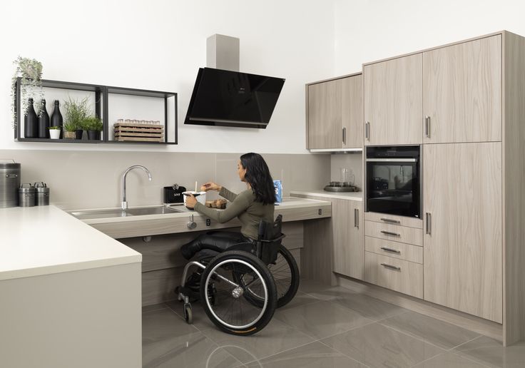 a woman in a wheel chair at the kitchen counter eating food from a bowl,