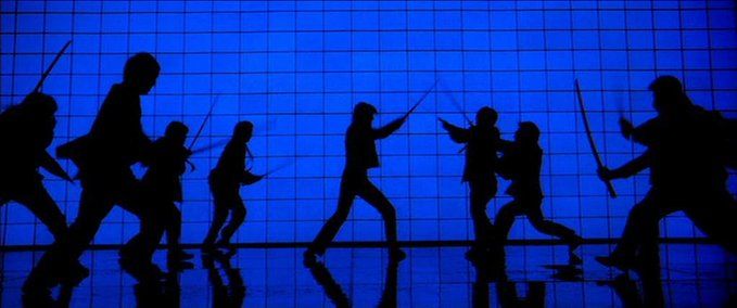 the silhouettes of people are walking in front of a blue wall with an advertisement on it