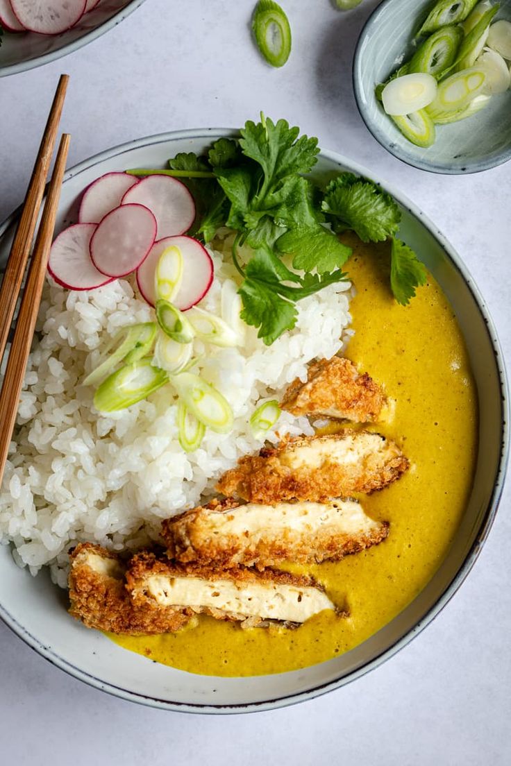 a white plate topped with rice and chicken next to chopsticks