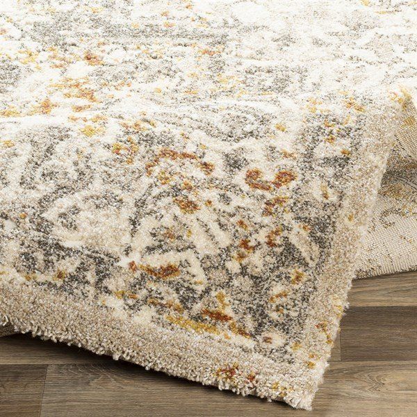 a white rug with yellow and brown flowers on the top is laying on a wooden floor