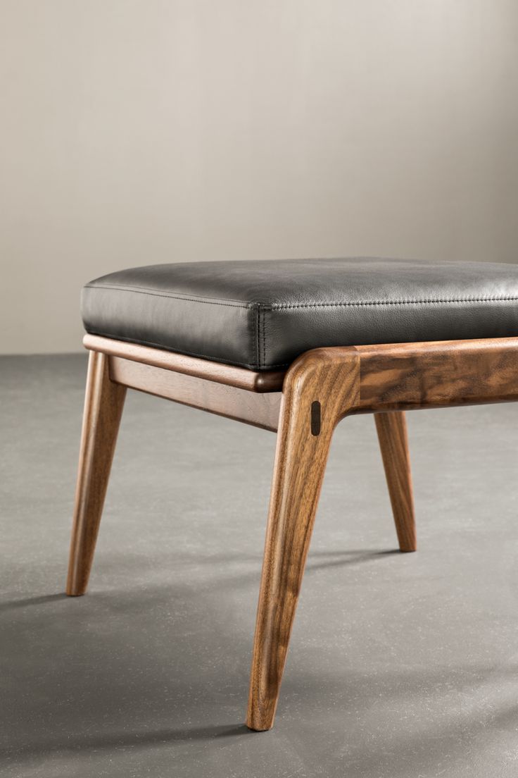 an upholstered wooden bench with black leather seat pad and back rest on concrete floor