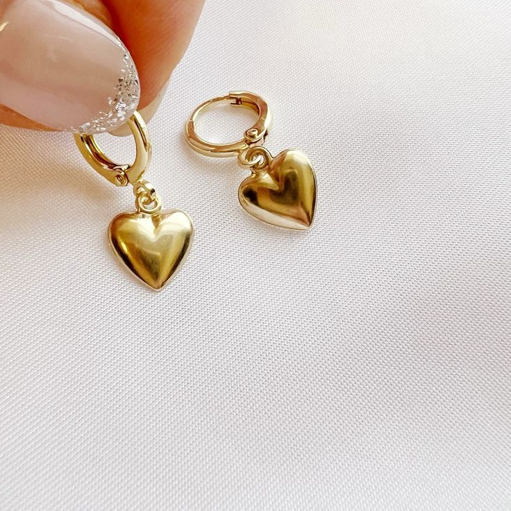 14k gold filled hearts dangle from huggie style hoops. Lightweight. Size: approx 1” 14k gold filled hoops Charms: 10mm Lever back closure Lead & nickel free / Hypoallergenic Handmade Includes 100% organic cotton jewelry pouch This item is made to order, packaged, and shipped with love from our studio located in West Chester, PA. *Click here to learn more about gold filled jewelry