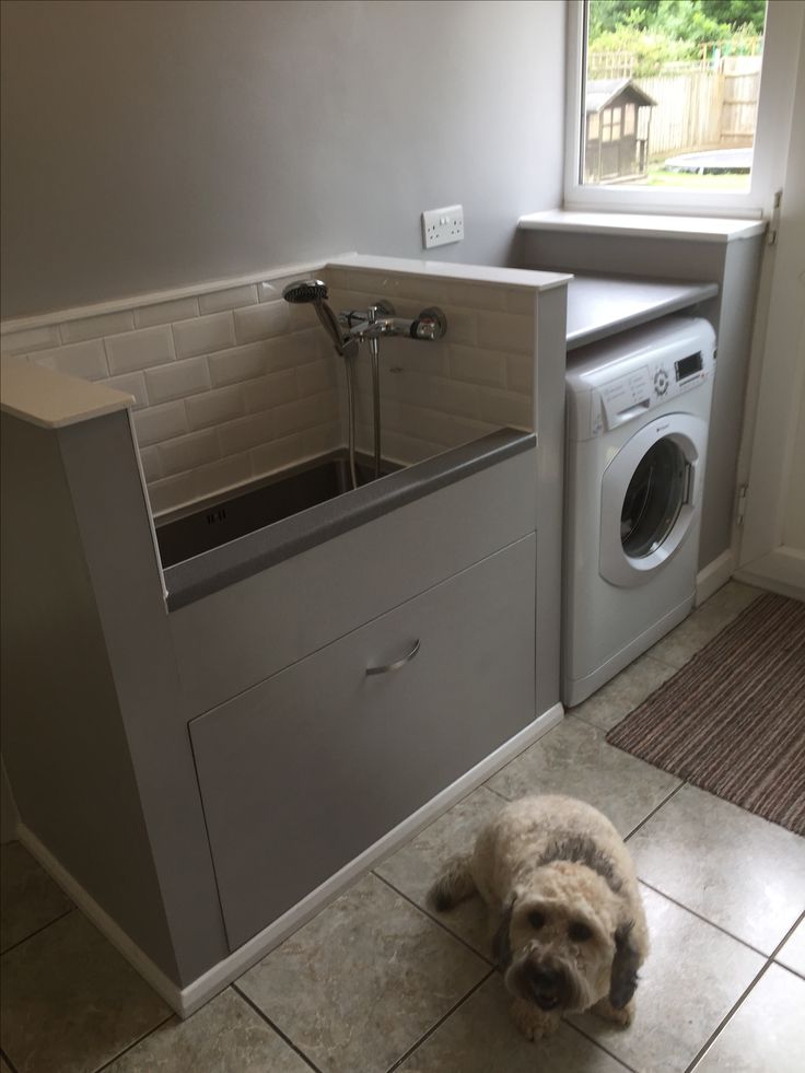 a dog laying on the floor next to a washer and dryer in a kitchen