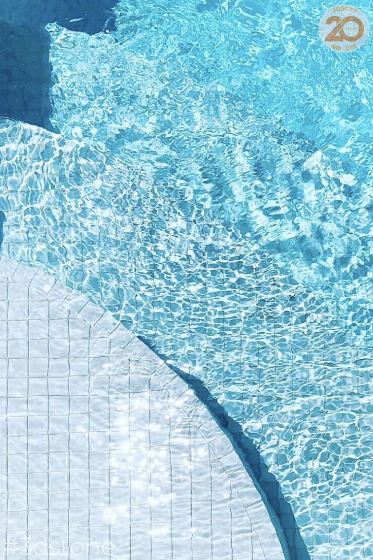 an overhead view of a swimming pool with clear blue water and sun reflecting on the surface