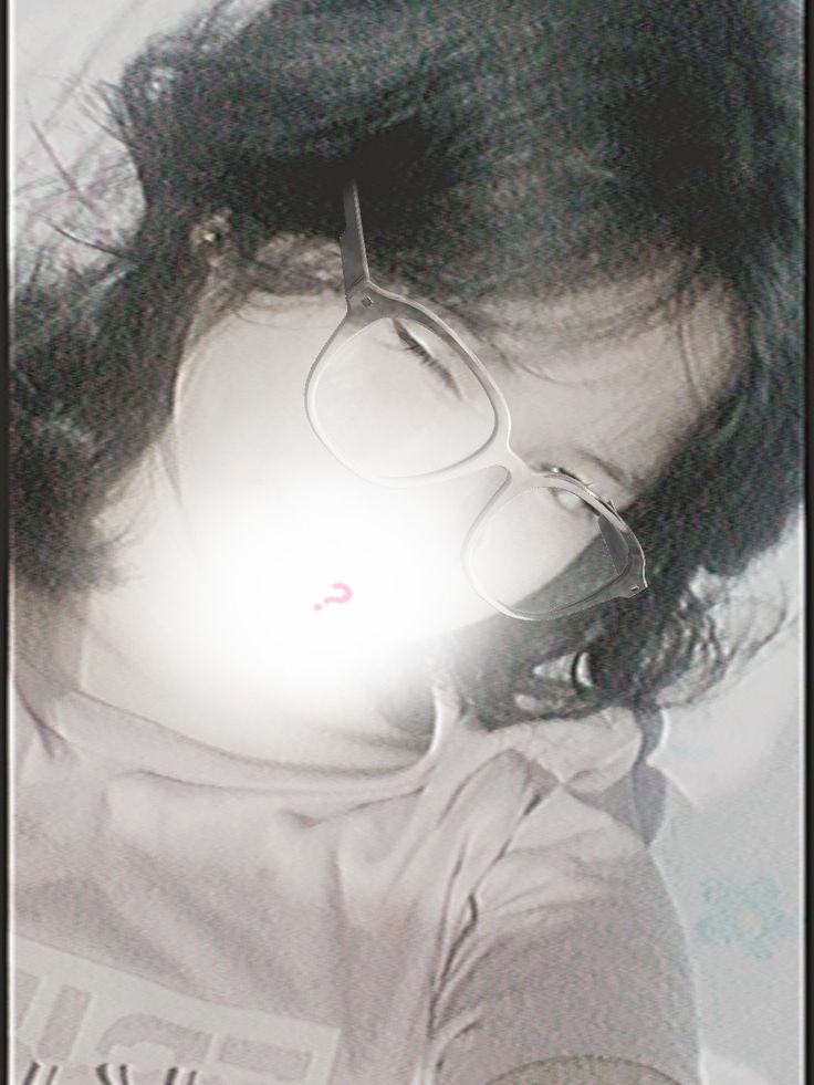 a woman with glasses laying on top of a white bed next to a light shining through her hair