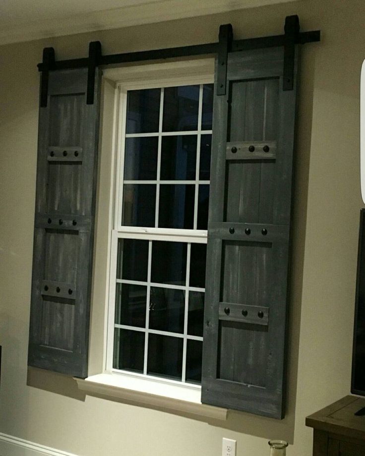 two windows with black shutters in a bedroom