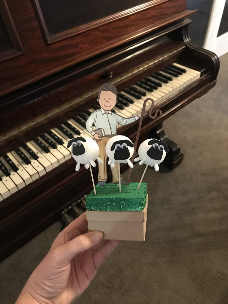 a hand holding a small box with cake toppers in front of a piano keyboard