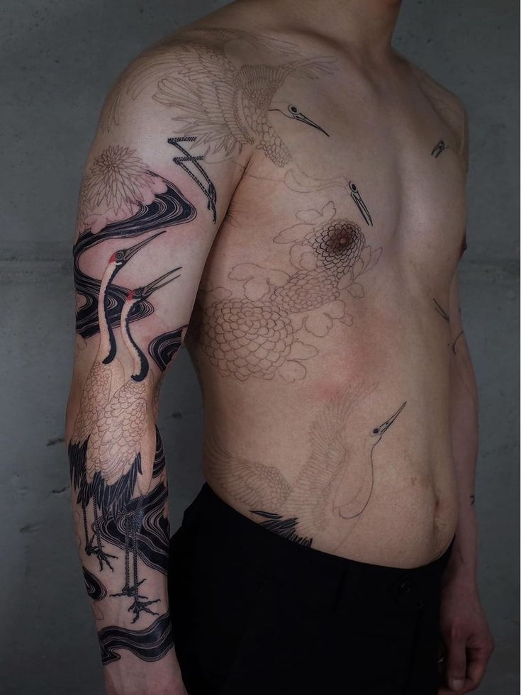 a man with a dragon tattoo on his arm and chest is standing in front of a wall