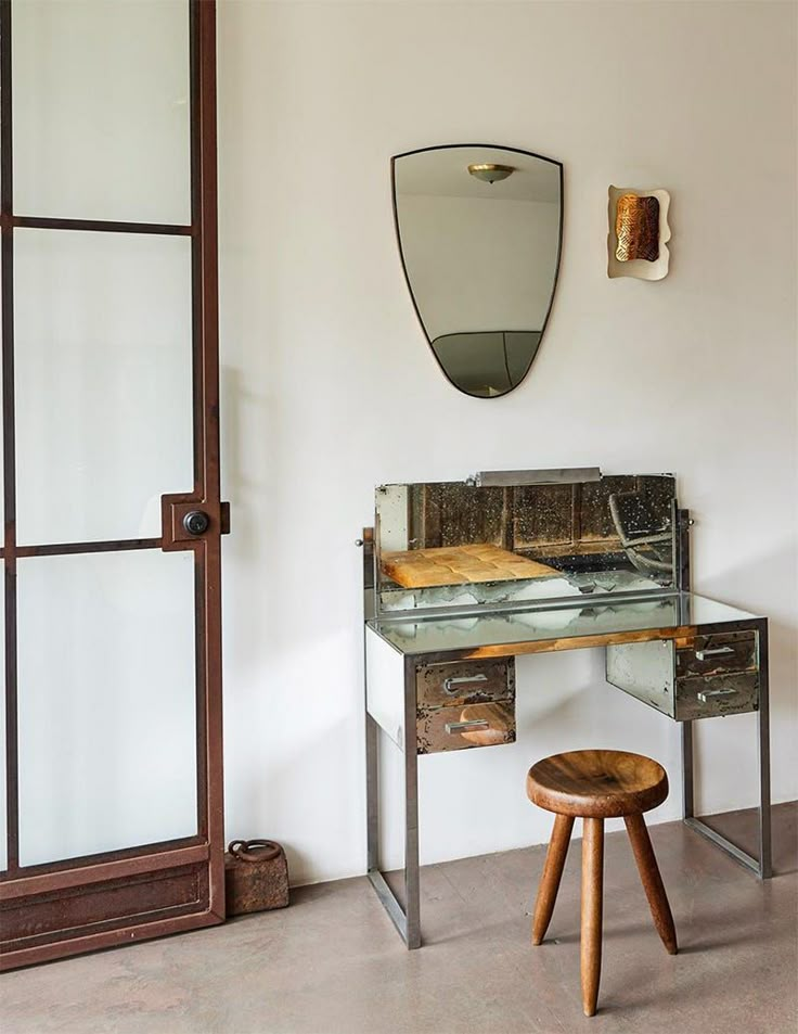 a desk with a mirror and stool in a room