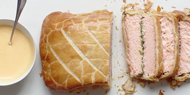 a sandwich cut in half next to a bowl of soup and spoon on a white surface